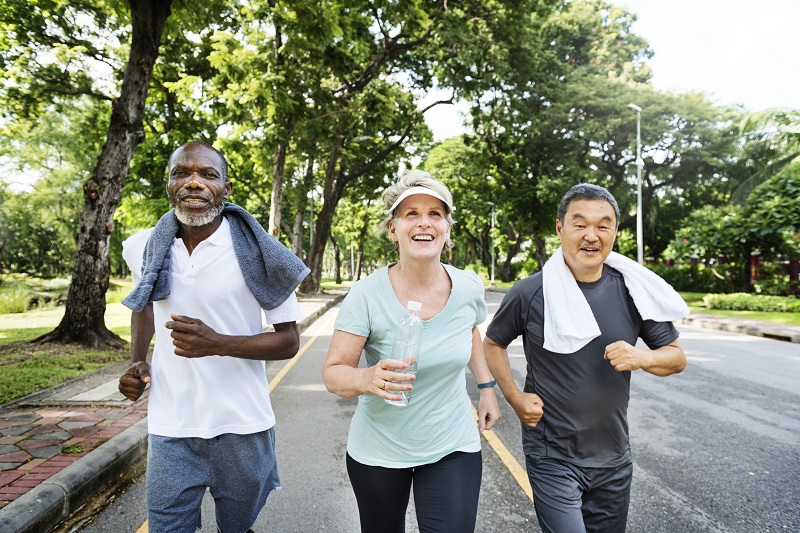 Over 50s staing healthy keeping fit - group of senior friends jogging together in a park